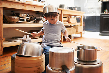 Image showing Rock star in the making. A young boy playing drums on pots and pans.