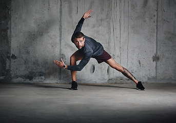 Image showing Getting ready to dash. Full length shot of a sporty young man stretching while exercising inside a parking lot.