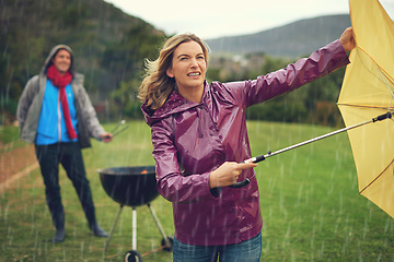 Image showing We wont let a little bad weather stop our barbeque. Shot of a couple trying to barbecue in the rain.