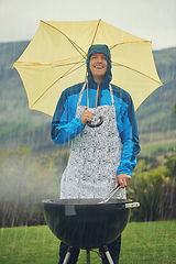 Image showing Its like liquid sunshine. Shot of a man happily barbecuing in the rain.