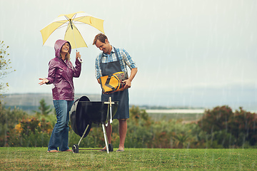 Image showing We barbecue anytime, anywhere. Shot of a couple happily barbecuing in the rain.