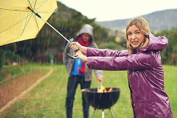 Image showing I think its clearing up. Shot of a couple trying to barbecue in the rain.