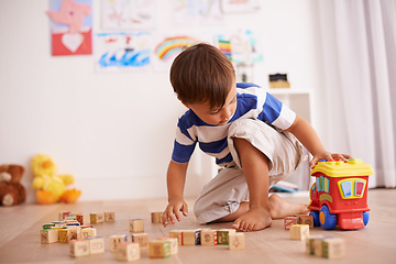 Image showing Playing and learning. Shot of a little boy playing with his building blocks and toy truck in his room.