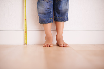 Image showing Getting taller by the day. Cropped shot of a young boy standing next to a tape measure.