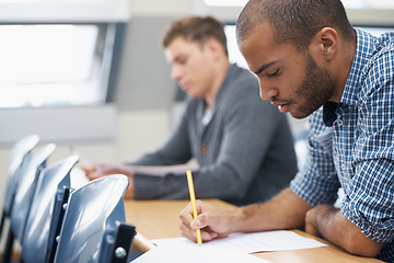 Image showing It all comes down to the test.... Two male students writing exam in a lecture hall.