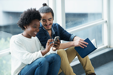 Image showing What did she say. A college couple sitting closely together looking at a message on one of their phones.