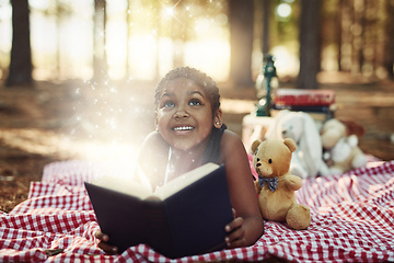 Image showing Let reading take you to a magical and wonderful world. Shot of a little girl reading a book with glowing pages in the woods.