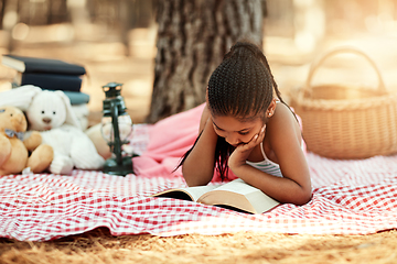 Image showing Reading opens new worlds for kids. Shot of a little girl reading a book with her toys in the woods.