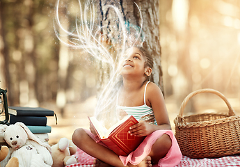 Image showing Open a book and you open your mind. Shot of a little girl reading a book with her toys in the woods.