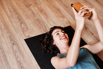 Image showing When your pocket device becomes your personal trainer. Shot of a young woman using a smartphone during a yoga session.