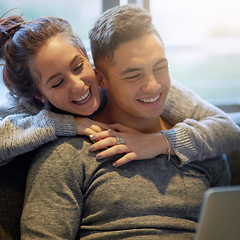 Image showing Sharing both love and laughter. Shot of an affectionate young couple surfing the net while relaxing on the sofa at home.