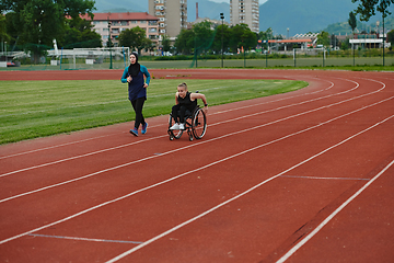 Image showing A Muslim woman in a burqa running together with a woman in a wheelchair on the marathon course, preparing for future competitions.