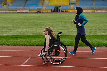 Image showing A Muslim woman in a burqa running together with a woman in a wheelchair on the marathon course, preparing for future competitions.