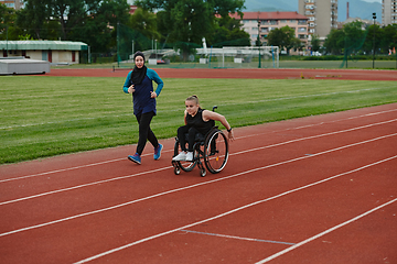 Image showing A Muslim woman in a burqa running together with a woman in a wheelchair on the marathon course, preparing for future competitions.