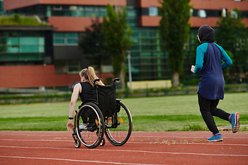 Image showing A Muslim woman in a burqa running together with a woman in a wheelchair on the marathon course, preparing for future competitions.