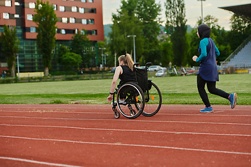 Image showing A Muslim woman in a burqa running together with a woman in a wheelchair on the marathon course, preparing for future competitions.