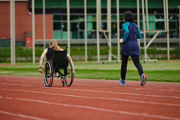 Image showing A Muslim woman in a burqa running together with a woman in a wheelchair on the marathon course, preparing for future competitions.