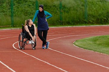 Image showing A Muslim woman wearing a burqa resting with a woman with disability after a hard training session on the marathon course