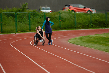 Image showing A Muslim woman wearing a burqa resting with a woman with disability after a hard training session on the marathon course