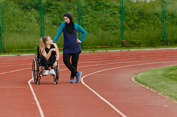 Image showing A Muslim woman wearing a burqa resting with a woman with disability after a hard training session on the marathon course