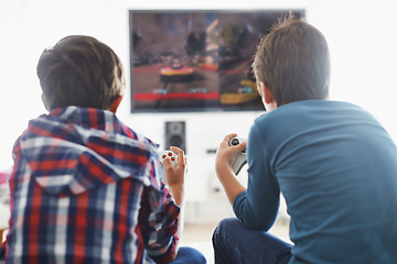 Image showing Game Time. Rearview shot of two boys playing a video game in the living room.