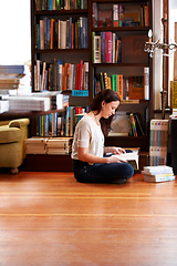 Image showing Getting her reading time in. A young woman sitting on the floor with her legs crossed and reading.