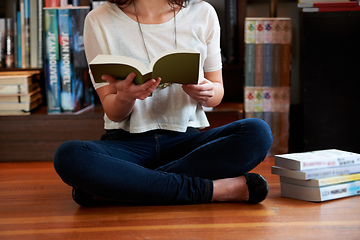 Image showing Reading a few passages.... A cropped shot of a young woman sitting on the floor of a bookshop and reading.