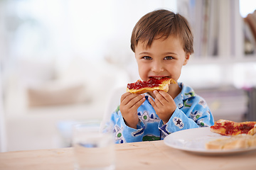 Image showing Nothing beats a good breakfast. A cute little boy eating toast with jam.