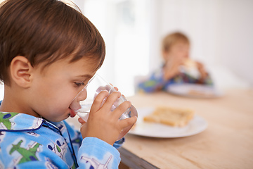 Image showing Washing it down. A cute little boy having a drink of water with breakfast.