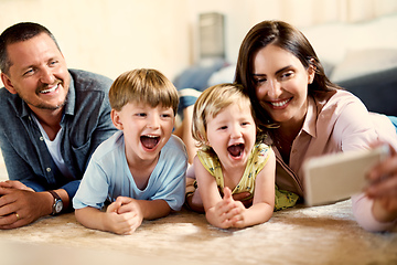 Image showing Dont need to ask kids twice to take a selfie. Shot of a happy young family taking selfies together at home.