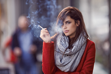 Image showing Ill bring the smoke, you bring the fire. Portrait of a beautiful and fashionable young woman smoking a cigarette in an urban setting.