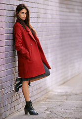 Image showing Winter ready in red. Portrait of a gorgeous young woman leaning against a brick wall in the city.