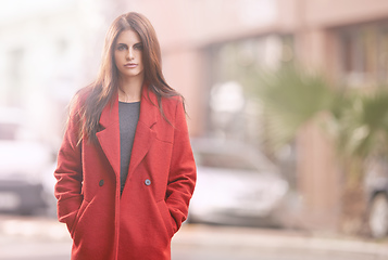 Image showing Look fab this fall. Portrait of a gorgeous young woman in a red winter coat standing in an urban setting.