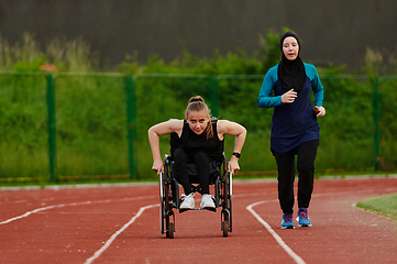 Image showing A Muslim woman in a burqa running together with a woman in a wheelchair on the marathon course, preparing for future competitions.