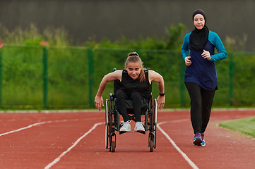 Image showing A Muslim woman in a burqa running together with a woman in a wheelchair on the marathon course, preparing for future competitions.