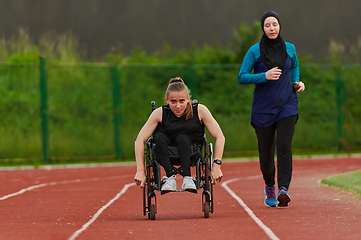 Image showing A Muslim woman in a burqa running together with a woman in a wheelchair on the marathon course, preparing for future competitions.