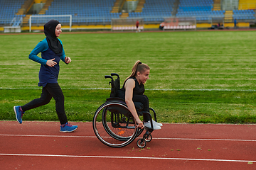 Image showing A Muslim woman in a burqa running together with a woman in a wheelchair on the marathon course, preparing for future competitions.