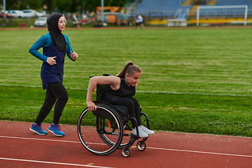 Image showing A Muslim woman in a burqa running together with a woman in a wheelchair on the marathon course, preparing for future competitions.