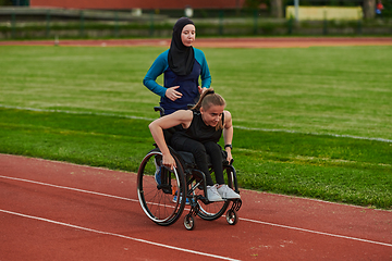 Image showing A Muslim woman in a burqa running together with a woman in a wheelchair on the marathon course, preparing for future competitions.