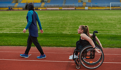 Image showing A Muslim woman in a burqa running together with a woman in a wheelchair on the marathon course, preparing for future competitions.