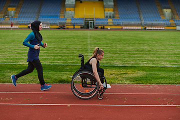 Image showing A Muslim woman in a burqa running together with a woman in a wheelchair on the marathon course, preparing for future competitions.