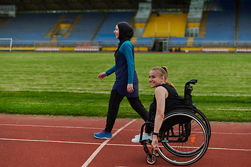 Image showing A Muslim woman in a burqa running together with a woman in a wheelchair on the marathon course, preparing for future competitions.