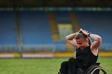 Image showing A Muslim woman in a burqa, an Islamic sports outfit, is doing body exercises, stretching her neck, legs and back after a hard training session on the marathon course.