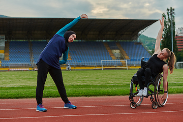 Image showing Two strong and inspiring women, one a Muslim wearing a burka and the other in a wheelchair stretching and preparing their bodies for a marathon race on the track