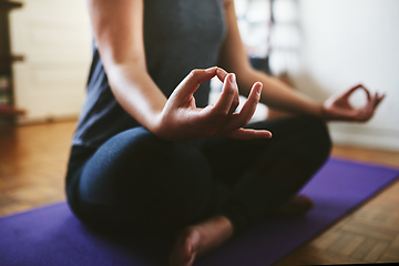 Image showing Finding my balance. Cropped shot of an unrecognizable woman sitting on a yoga mat and meditating alone in her home.