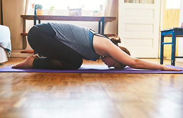 Image showing Feeling the stretch in my shoulders. Cropped shot of an attractive young woman doing yoga and holding a childs pose in her home.