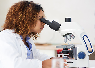Image showing Taking a closer look. Cropped shot of a young female scientist looking into a microscope.