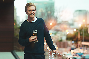 Image showing Let the night begin. Portrait of a young man relaxing on a balcony while enjoying a beer.