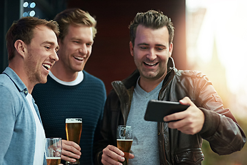 Image showing Check out this video. Shot of a group of friends enjoying a beer together while standing on a balcony together.