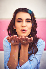 Image showing There is nothing wrong with celebrating everyday. Portrait of a beautiful young woman blowing confetti outside.